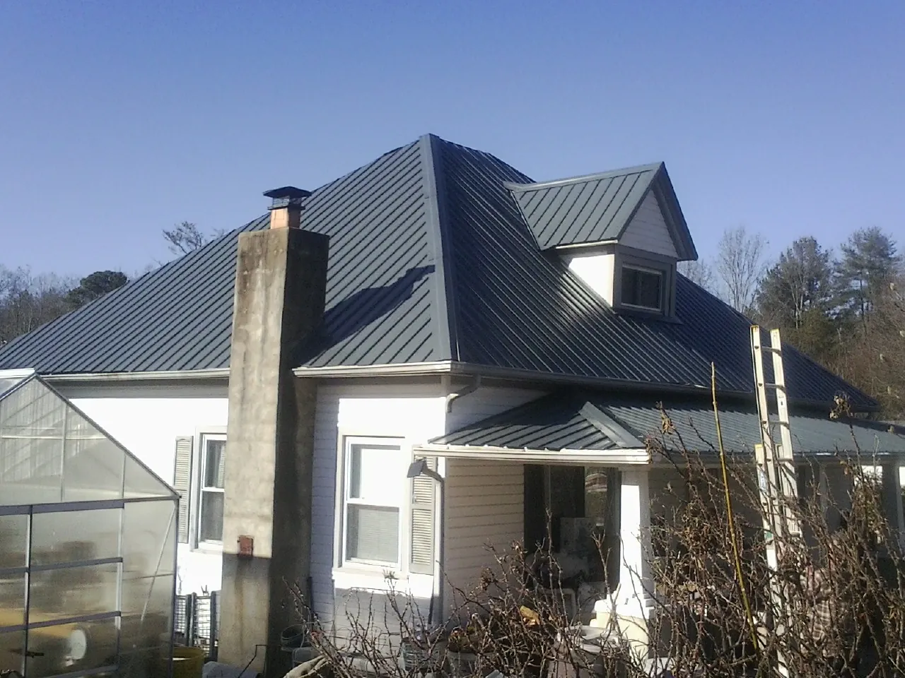 Dark blue standing seam metal roof on a white farmhouse with dormer — Slate & Tile Roof Repair by Roofing Brothers in Moscow Mills