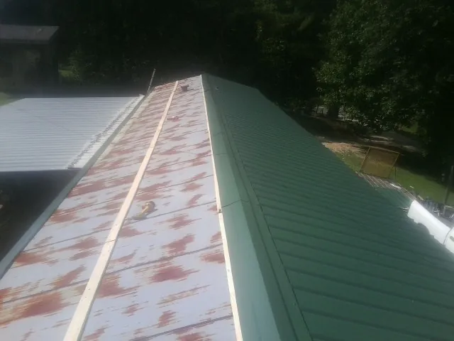 Old rusted panels beside newly installed green metal roofing — Wind Damage Roof Repair by Roofing Brothers in Moscow Mills