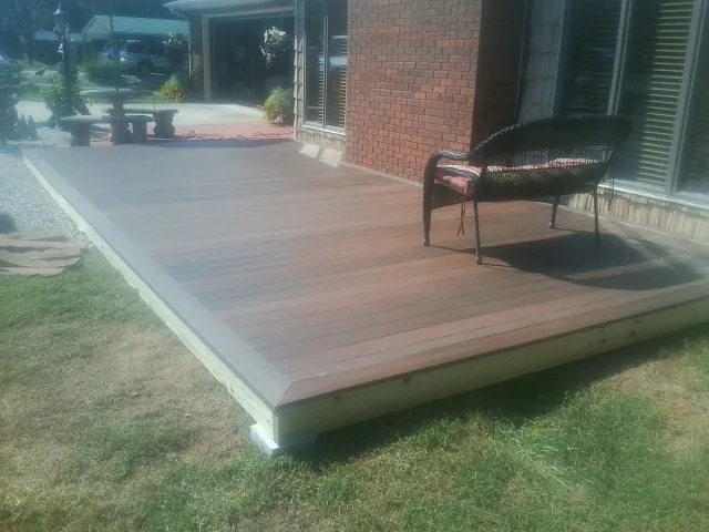 New wood deck and wicker chair beside a brick house in Moscow Mills