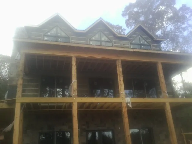 Dormers and porch framing on a large log home under construction — Roof Coating work by our crew in Moscow Mills