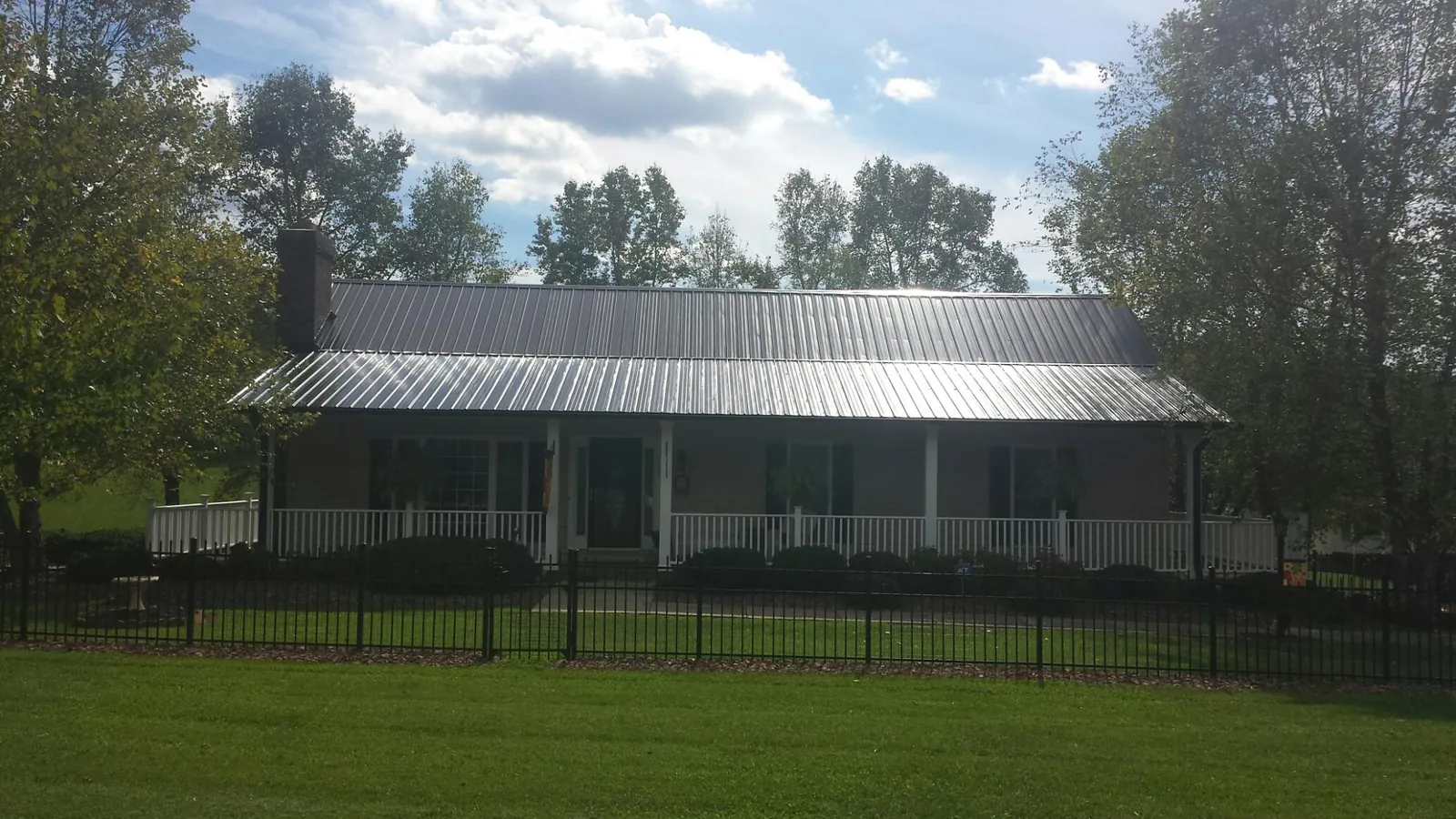 Gray metal roof on a brick ranch with a full width front porch — Gutter Guard Installation work by our crew in Moscow Mills