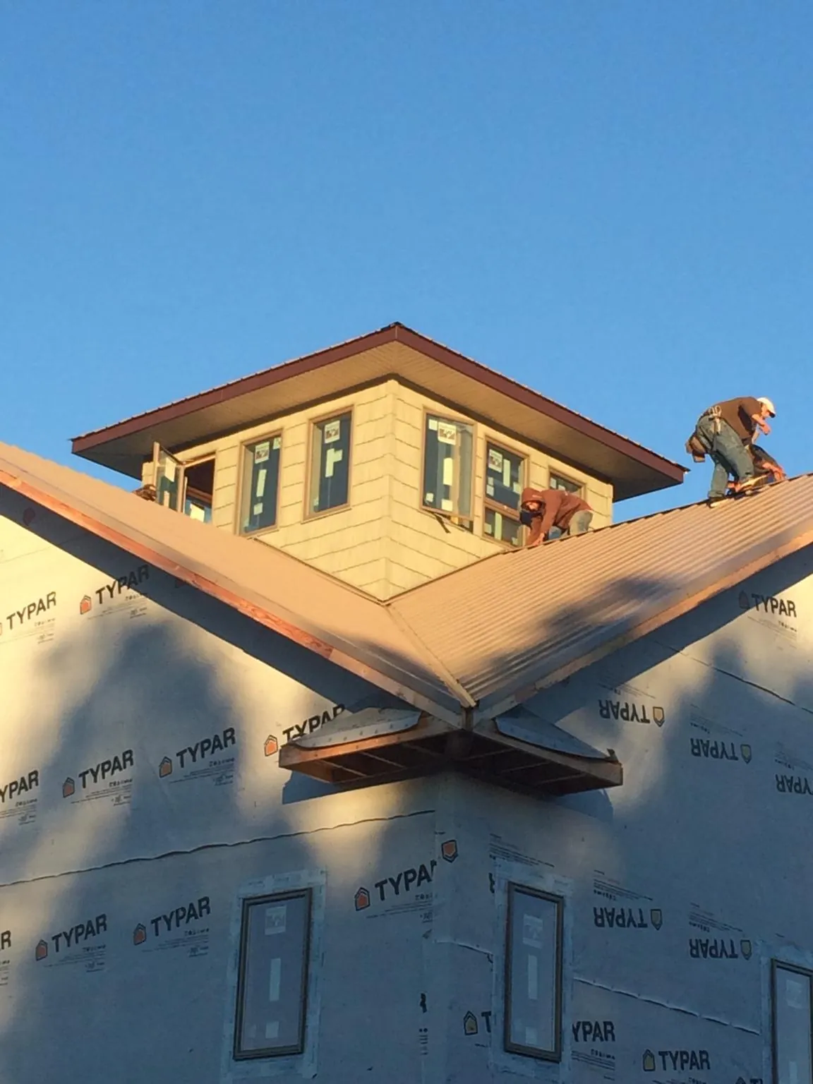 Roofers working around a rooftop cupola on a new metal roof at sunset — Roof Waterproofing in Moscow Mills by Roofing Brothers